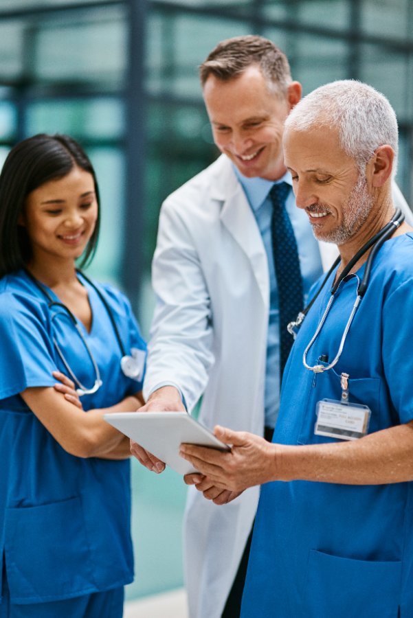 A nurse, physician, and charge nurse reviewing a tablet together