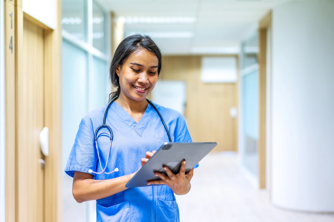 A nurse reviewing huddle guidance on a tablet in a unit corridor