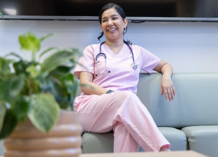 A nurse in pink scrubs seated in a staff lounge
